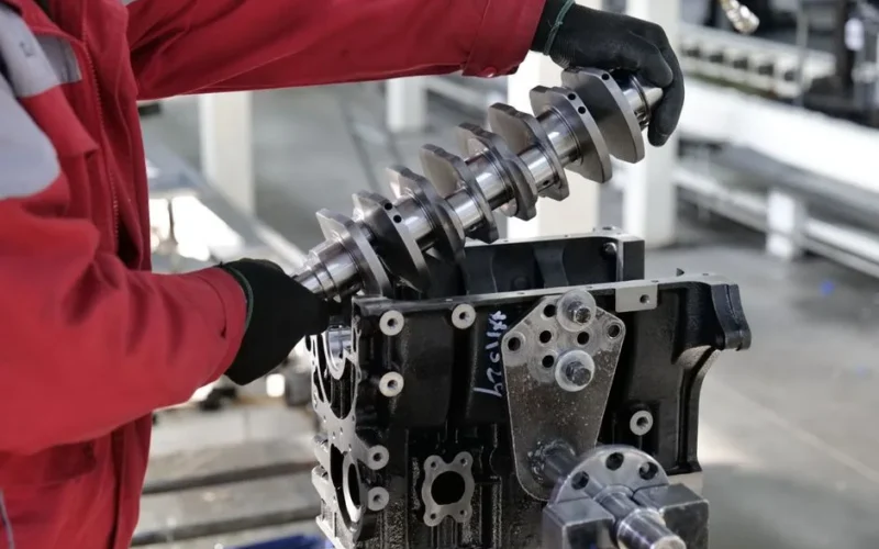 Mechanic working on a crankshaft installation in an engine block in an industrial setting.