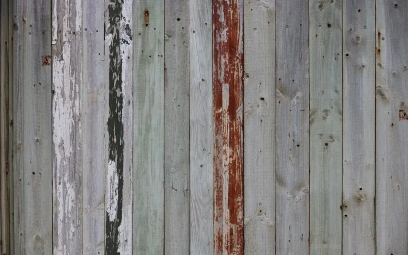 Close-up of a weathered wooden fence with peeling paint showcasing rustic texture.