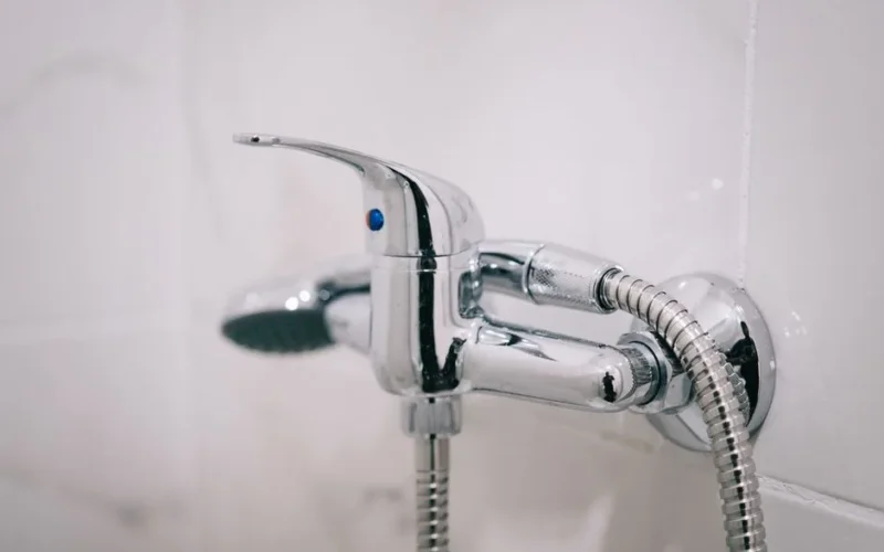 A detailed view of a sleek chrome shower faucet in a clean bathroom setting.