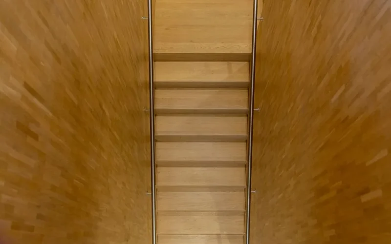 Top-down view of a simplistic wooden staircase with a warm minimalistic design.