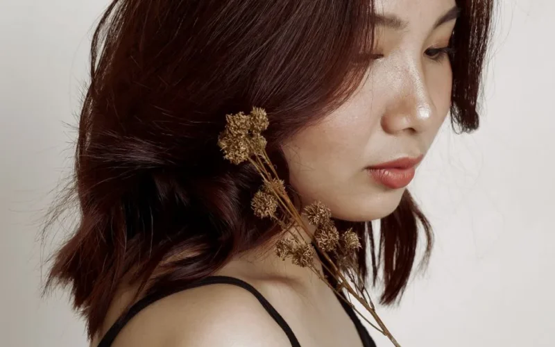 Close-up portrait of a woman with brunette hair and dried flowers, showcasing elegance and natural beauty.
