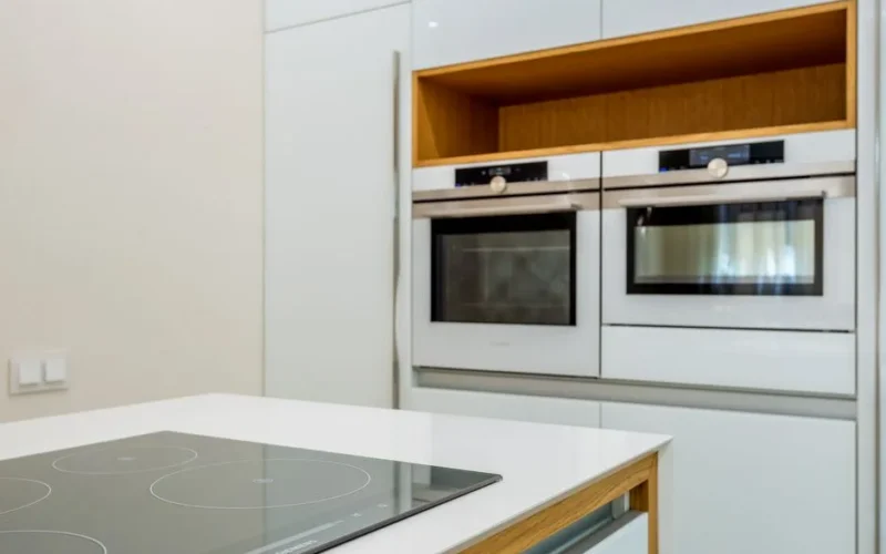 Interior of contemporary light kitchen with white ovens and clean new stove in modern apartment