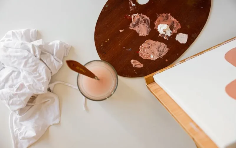 Top view of a painting setup with paint palette, brushes, and canvas, perfect for creative projects.