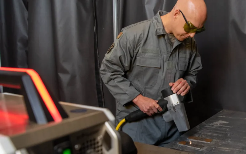 U.S. Air Force Brig. Gen. Josh Olson, 86th Airlift Wing commander, uses a laser paint removal system during a visit to the 86th Maintenance Squadron metals technology section at Ramstein Air Base, Germany, April 13, 2022. The newly acquired technology has allowed the section to become a one-stop shop for processing most Aero Space Ground Equipment repairs. (U.S. Air Force photo by Staff Sgt. Emmeline James)