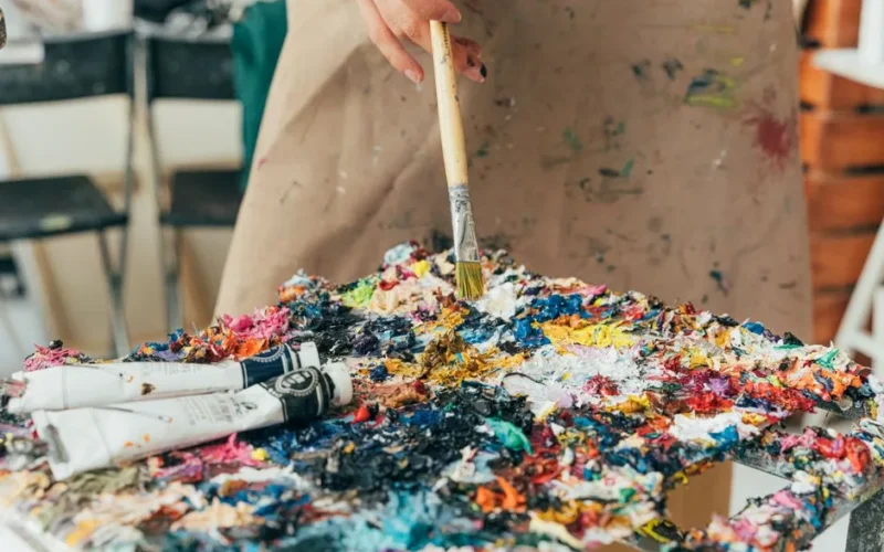 Vibrant paint palette with brush and tubes in an artist's studio setting.