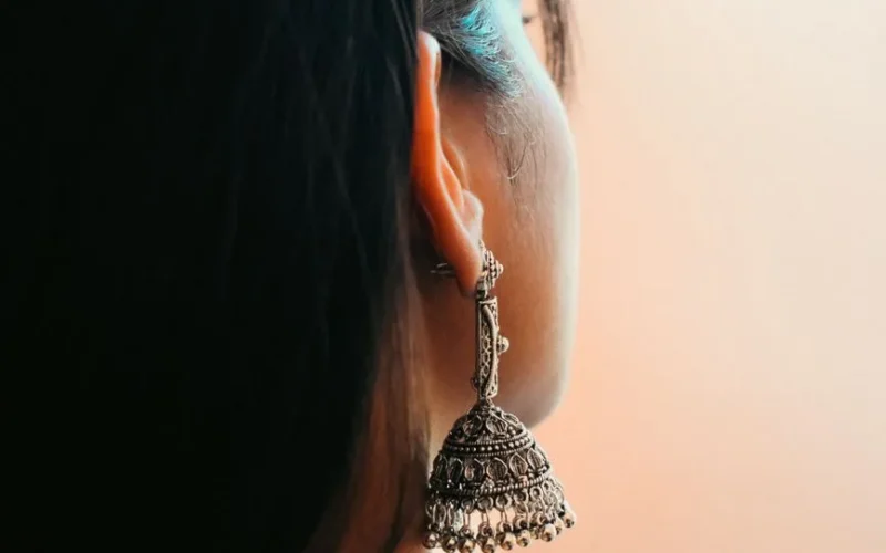 Detailed view of a woman's ear adorned with intricate silver earring.