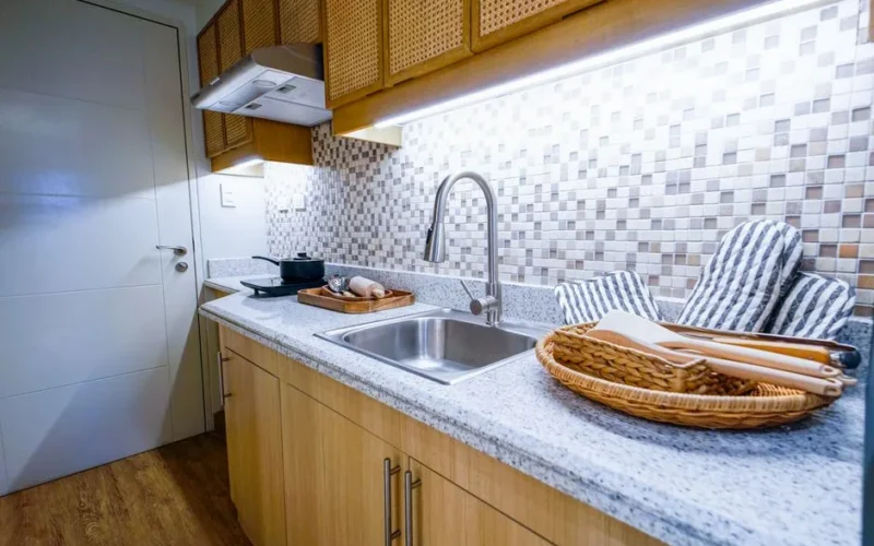 A bright kitchenette featuring a sleek sink, stylish backsplash, and organized utensils.