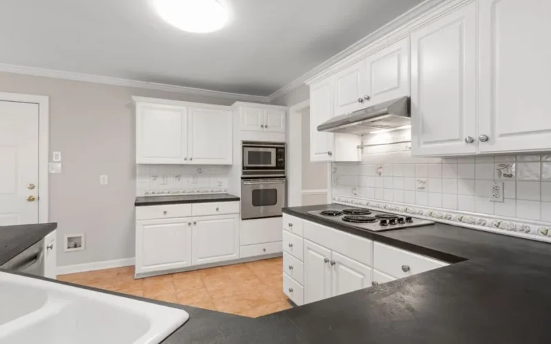A clean and modern kitchen featuring white cabinets and black countertops with elegant lighting.