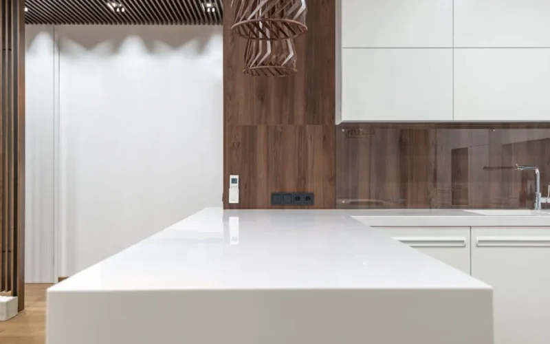 Clean empty kitchen counter with sink and cupboards on wooden wall located in spacious apartment with stylish design at home