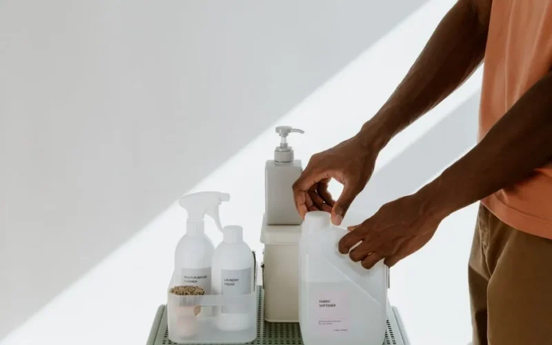 Man arranging cleaning products on a shelf, highlighting tidiness and organization.