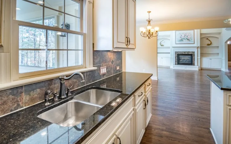 Spacious kitchen with granite countertops, stainless steel sink, and elegant chandelier lighting.