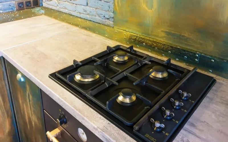 Close-up of a sleek modern gas stove on a rustic industrial style kitchen counter.