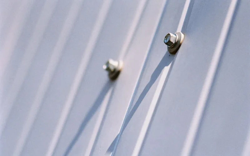 Detailed view of metal screws securing a steel sheet, highlighting durability.