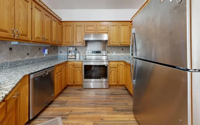 A well-lit kitchen featuring stainless steel appliances and wooden cabinets.