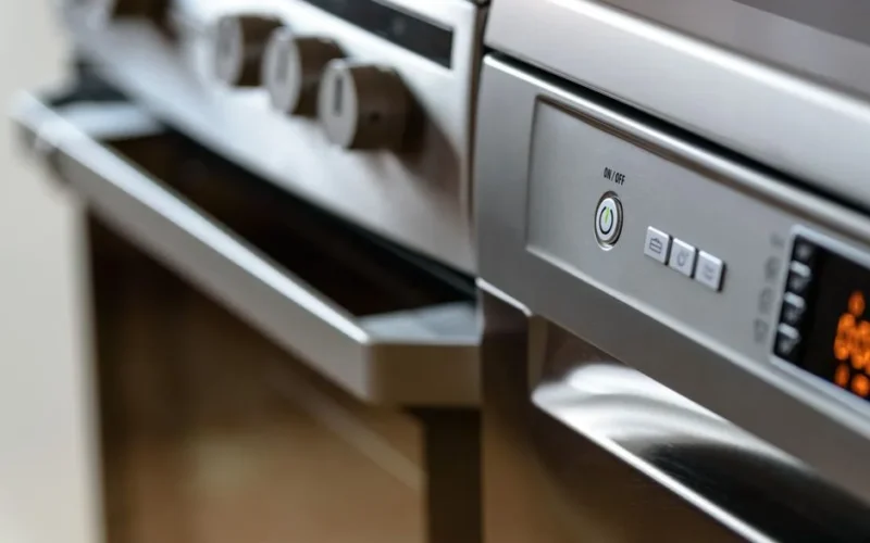 Close-up view of modern stainless steel kitchen appliances with focus on dishwasher and oven.