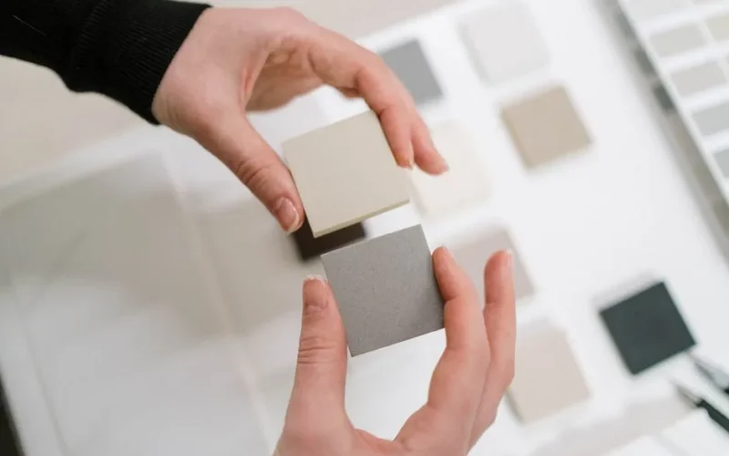 Hands holding neutral color swatches for interior design selection.