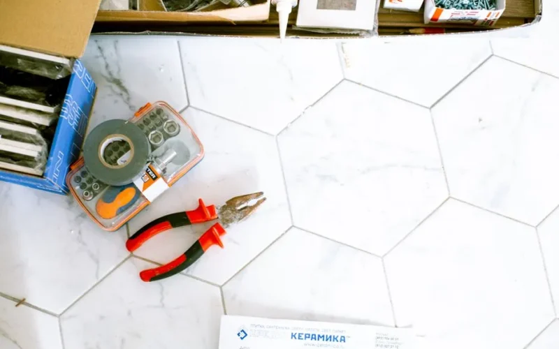 A selection of home renovation tools placed on a white tiled floor, ready for use.