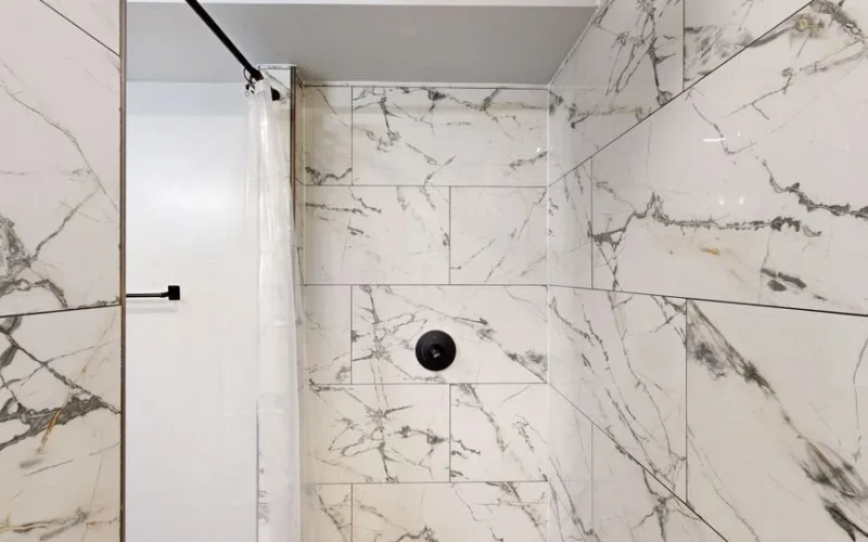 Luxurious modern shower with white and gray marble tiles and minimal design.
