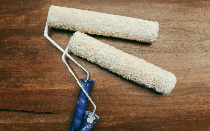 Two paint rollers over a wooden surface, perfect for home renovation concepts.
