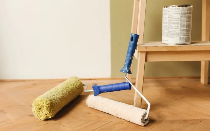 Paint rollers on wooden floor surface next to a can, ready for home renovation.