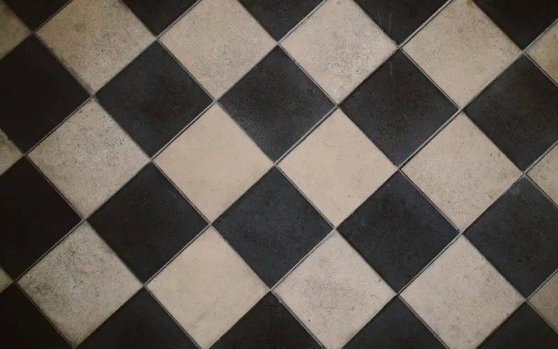 Diagonal black and white checkered floor tiles with a geometric design.