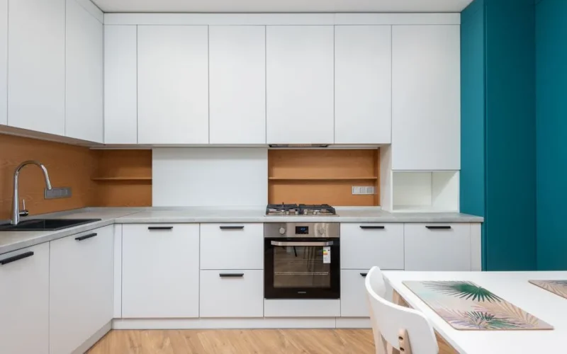 Contemporary kitchen interior with cabinets and gas stove above oven against table with placemats in house