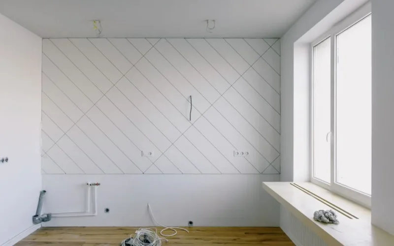 Laying pipes and wiring during repairs in kitchen room with white walls and big window