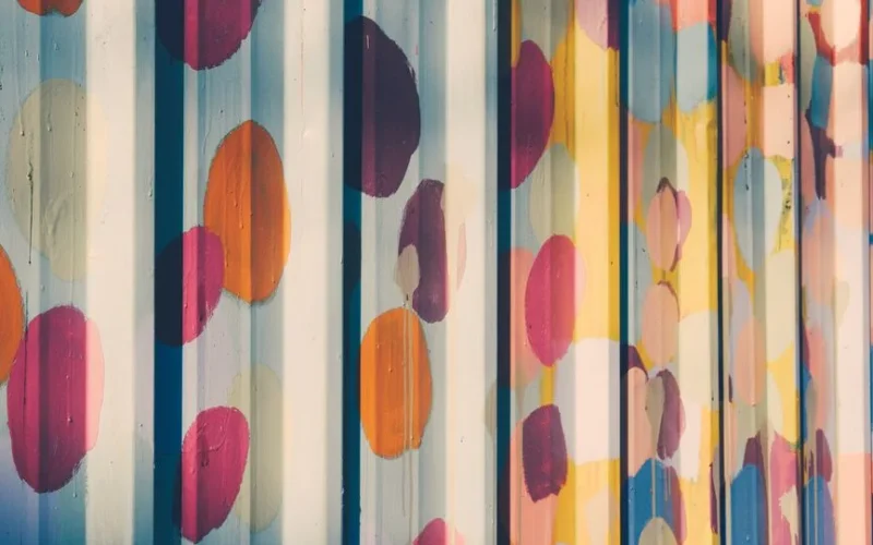 Artistic metal wall displaying a colorful painted pattern with a corrugated texture.