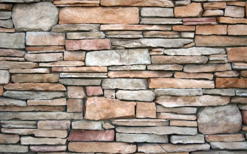 High-resolution image of a natural stone wall with various textures and earthy tones.