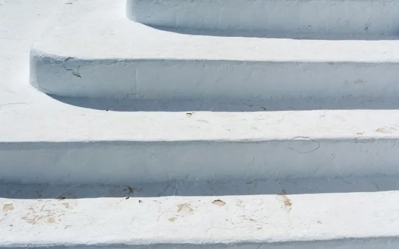 A close-up of textured white steps outdoors, showing winter wear in an urban setting.