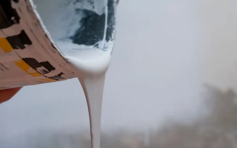 A close-up of white paint flowing from a can, capturing the creative process.