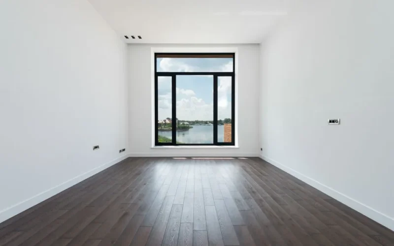 Interior of modern spacious light room with wooden laminate floor white walls and panoramic windows