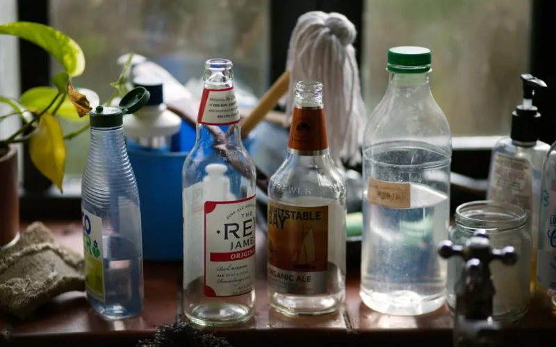 A collection of empty glass bottles and plastic containers on a kitchen countertop.